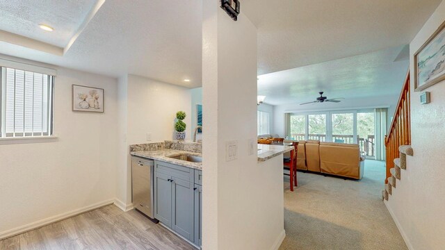 kitchen with light wood-type flooring, a textured ceiling, sink, gray cabinetry, and stainless steel dishwasher