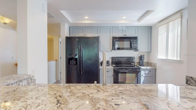 kitchen featuring black appliances, a tray ceiling, and gray cabinets