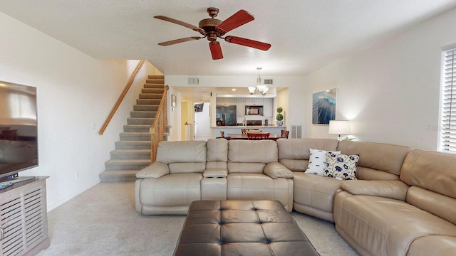 carpeted living room with ceiling fan with notable chandelier and plenty of natural light