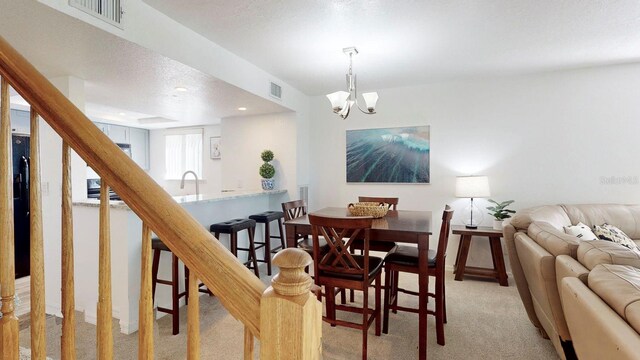 carpeted dining space with a notable chandelier, a textured ceiling, and sink