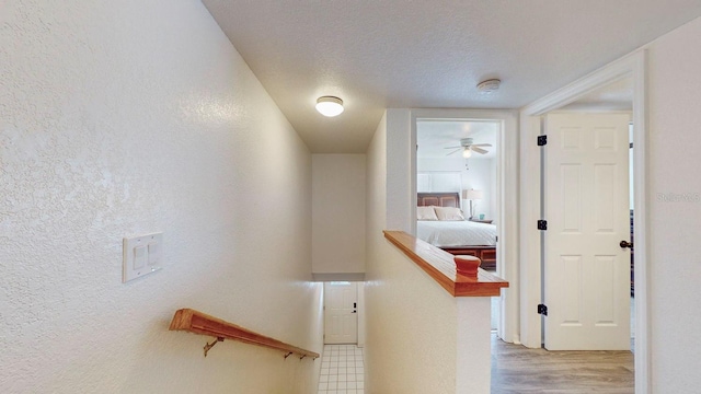 hallway with light wood-type flooring and a textured ceiling