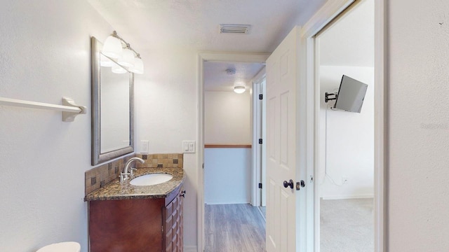 bathroom featuring wood-type flooring, vanity, a textured ceiling, and tasteful backsplash