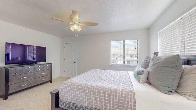 bedroom featuring ceiling fan, light colored carpet, and a textured ceiling