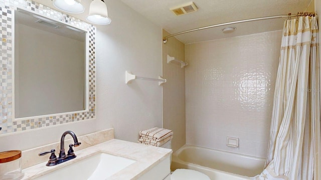 full bathroom with vanity, toilet, a textured ceiling, and shower / tub combo with curtain