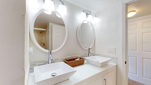 bathroom with a textured ceiling, a shower, and vanity