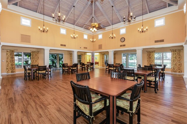 dining room featuring beam ceiling, light hardwood / wood-style flooring, high vaulted ceiling, wooden ceiling, and ornate columns