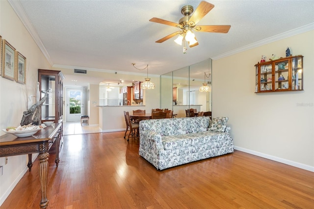 living room featuring a textured ceiling, wood-type flooring, crown molding, and ceiling fan