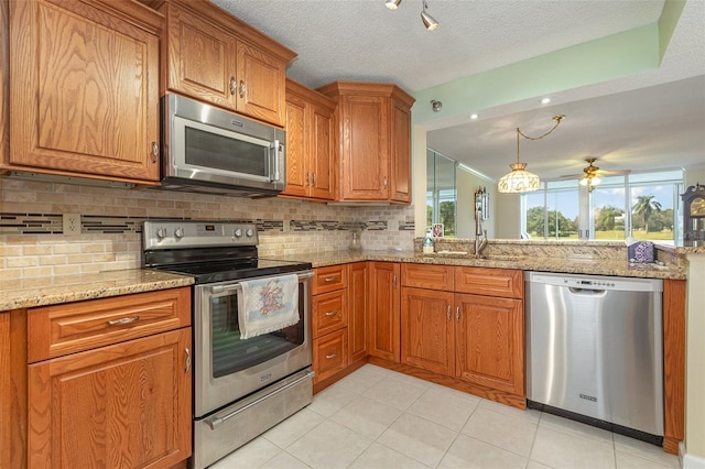 kitchen with backsplash, light stone countertops, stainless steel appliances, ceiling fan, and sink