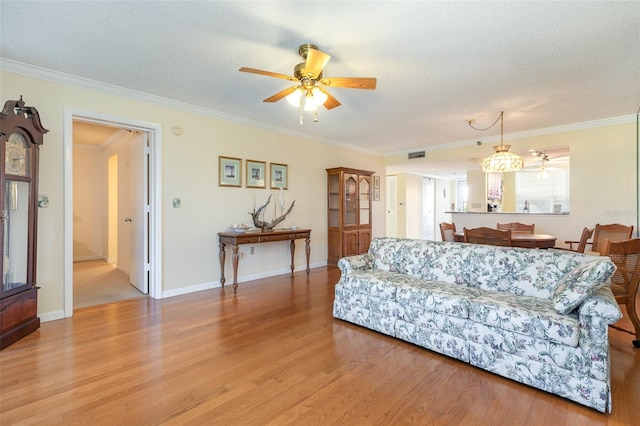 living room featuring ornamental molding, light hardwood / wood-style floors, ceiling fan, and a textured ceiling