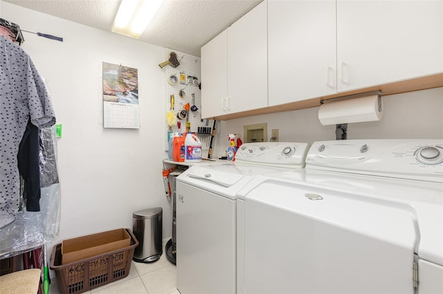 washroom featuring a textured ceiling, light tile patterned floors, washer and dryer, and cabinets