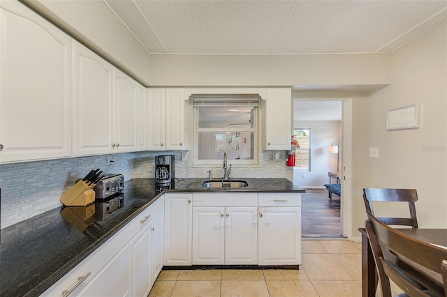 kitchen featuring dark stone countertops, sink, and white cabinets