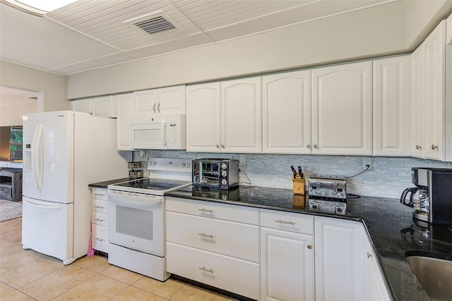 kitchen with dark stone counters, light tile patterned flooring, white cabinetry, white appliances, and backsplash