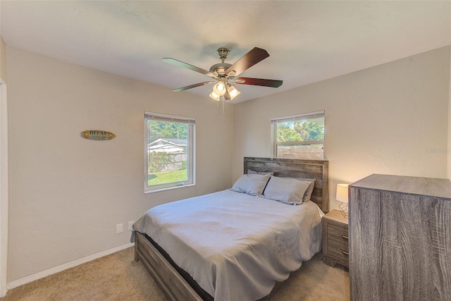 bedroom featuring multiple windows, light carpet, and ceiling fan