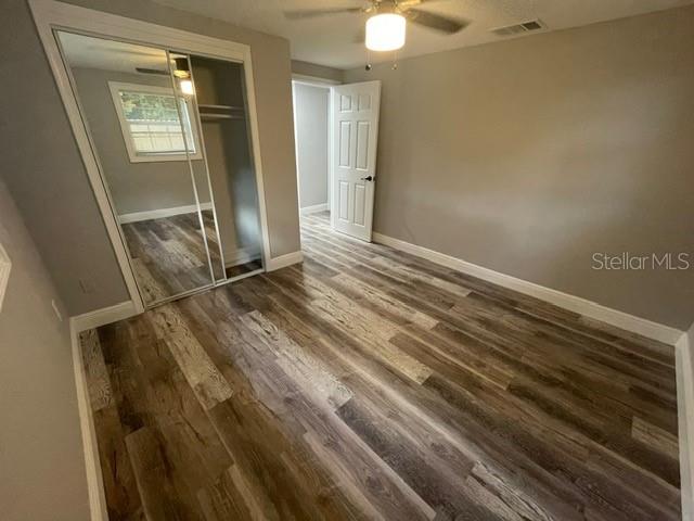 unfurnished bedroom featuring dark wood-type flooring, a closet, and ceiling fan