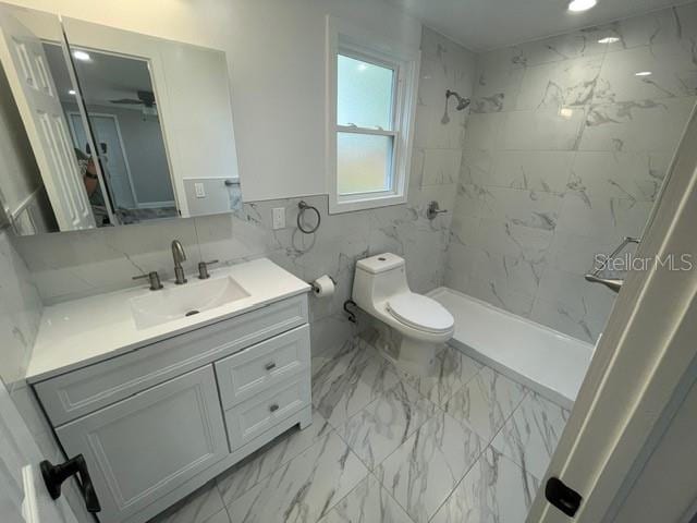 bathroom featuring vanity, toilet, and tiled shower