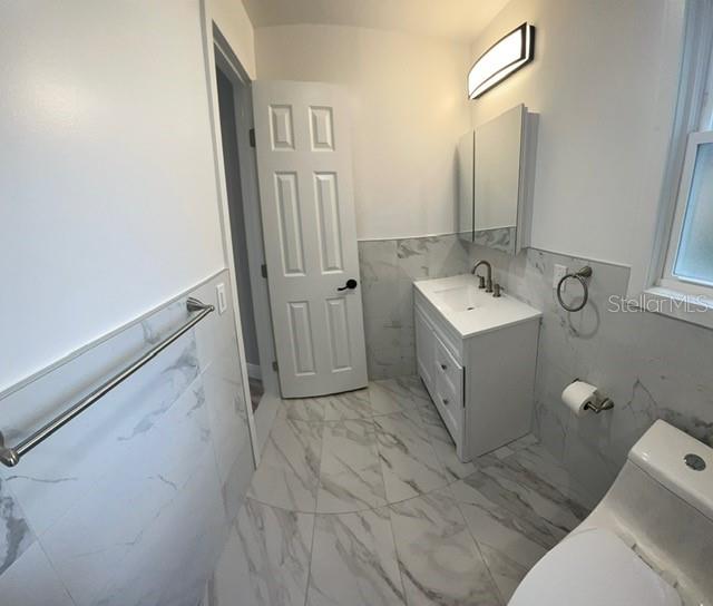 bathroom with tile walls, vanity, and toilet