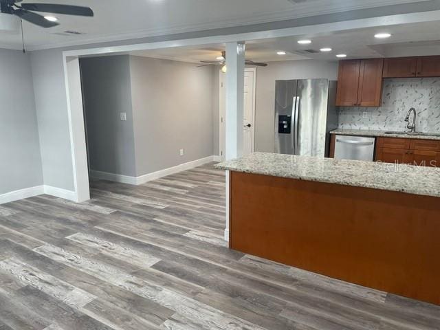 kitchen featuring backsplash, appliances with stainless steel finishes, light stone countertops, ornamental molding, and dark hardwood / wood-style floors