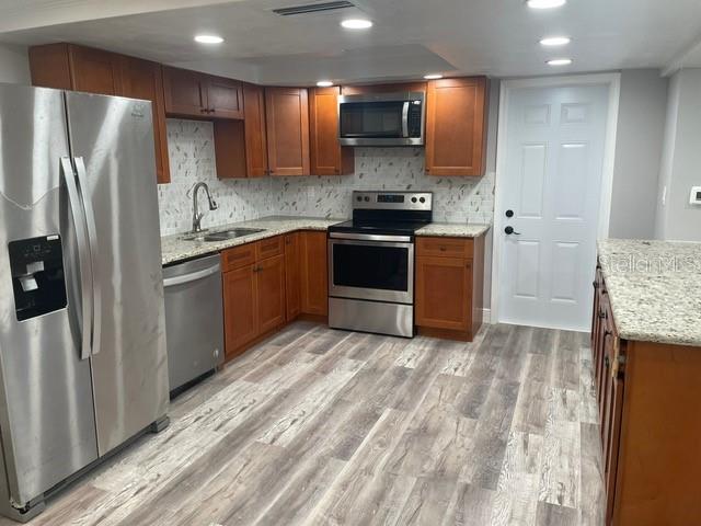 kitchen featuring sink, decorative backsplash, stainless steel appliances, and light hardwood / wood-style floors