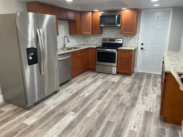 kitchen with light hardwood / wood-style flooring, tasteful backsplash, stainless steel appliances, and sink