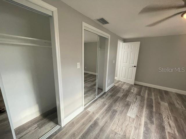 unfurnished bedroom with a closet, ceiling fan, and dark wood-type flooring