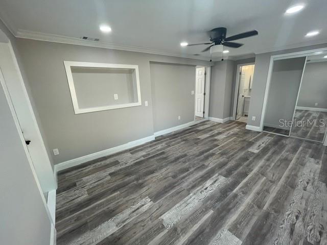 unfurnished bedroom featuring a closet, ornamental molding, ceiling fan, and dark hardwood / wood-style flooring