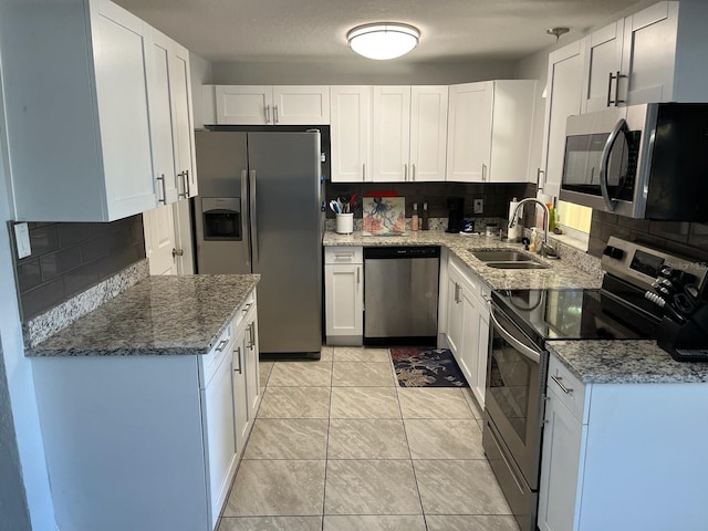 kitchen with light tile patterned flooring, white cabinetry, tasteful backsplash, stainless steel appliances, and sink