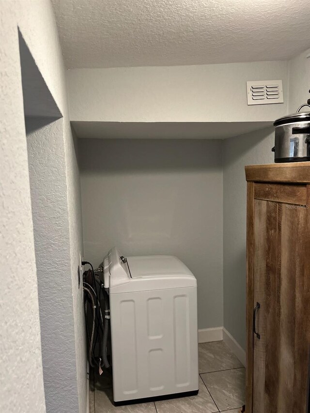 washroom featuring washer / clothes dryer, a textured ceiling, and light tile patterned floors