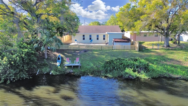 back of house featuring a water view, stucco siding, a yard, a fenced backyard, and a patio