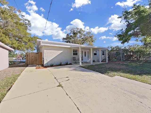 view of front of property featuring stucco siding, fence, a porch, and a gate