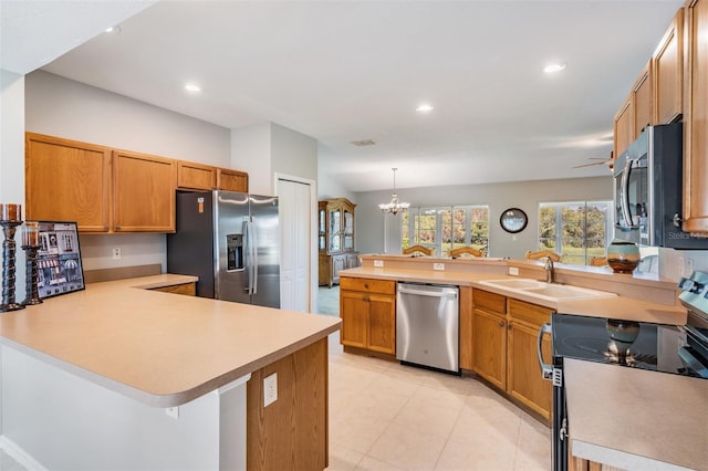 kitchen with stainless steel appliances, kitchen peninsula, a chandelier, sink, and decorative light fixtures