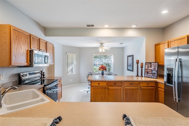 kitchen with stainless steel appliances, light tile patterned flooring, sink, kitchen peninsula, and ceiling fan