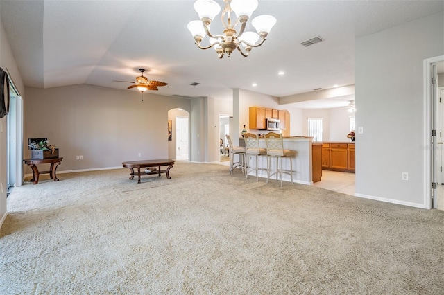 living room featuring ceiling fan with notable chandelier, light carpet, and vaulted ceiling