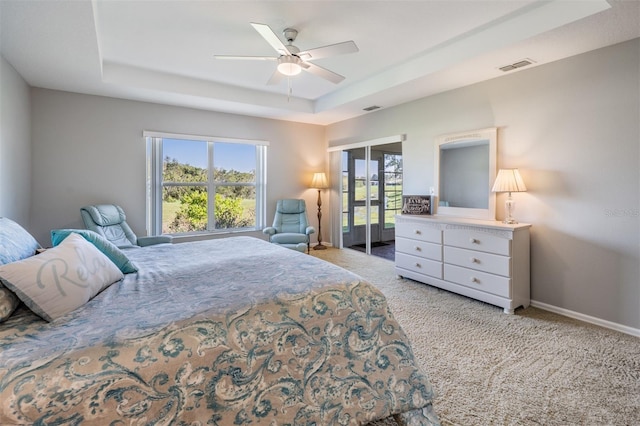 carpeted bedroom featuring a tray ceiling and ceiling fan