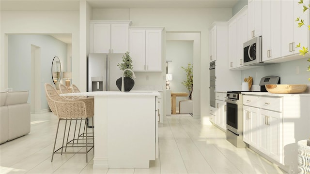 kitchen featuring appliances with stainless steel finishes, a kitchen breakfast bar, white cabinetry, and a kitchen island