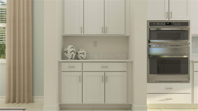 kitchen with white cabinetry, stainless steel double oven, and light tile patterned floors