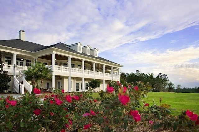 back of property featuring a balcony and a yard