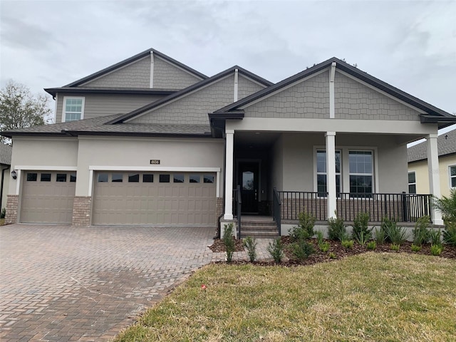 craftsman house with a front yard, a garage, and covered porch