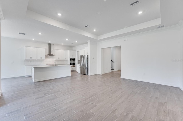 unfurnished living room with light hardwood / wood-style flooring and a raised ceiling