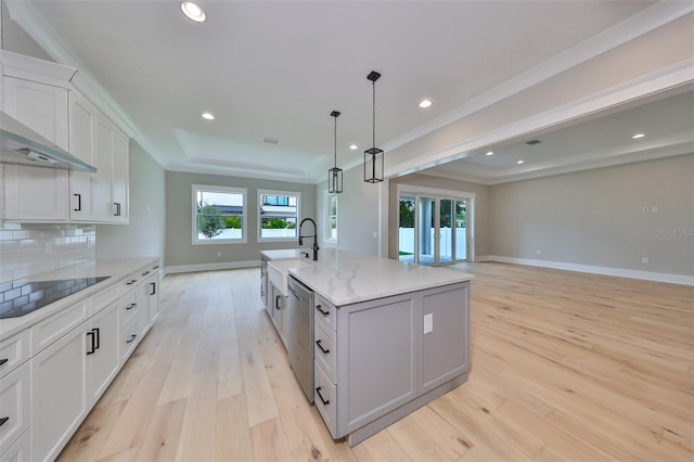 kitchen with black electric cooktop, white cabinets, a center island with sink, and light hardwood / wood-style flooring