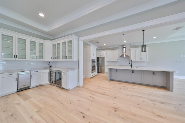 kitchen with light wood-type flooring, hanging light fixtures, an island with sink, and white cabinets