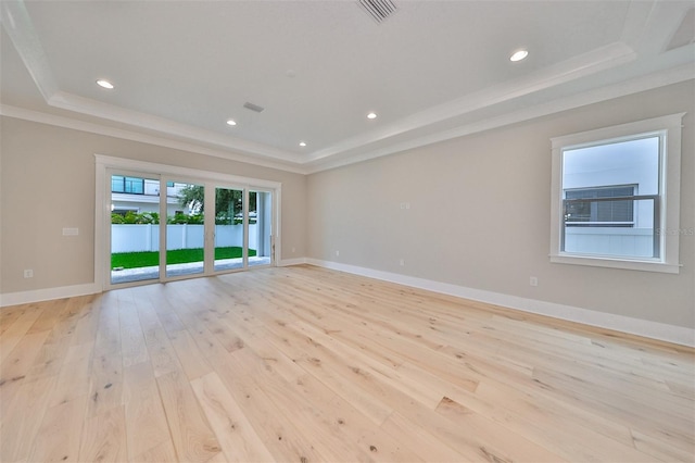 spare room with light wood-type flooring, crown molding, and a tray ceiling