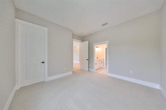 unfurnished bedroom with ensuite bath and light carpet