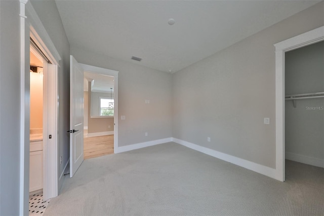 unfurnished bedroom with light carpet, a closet, and a walk in closet