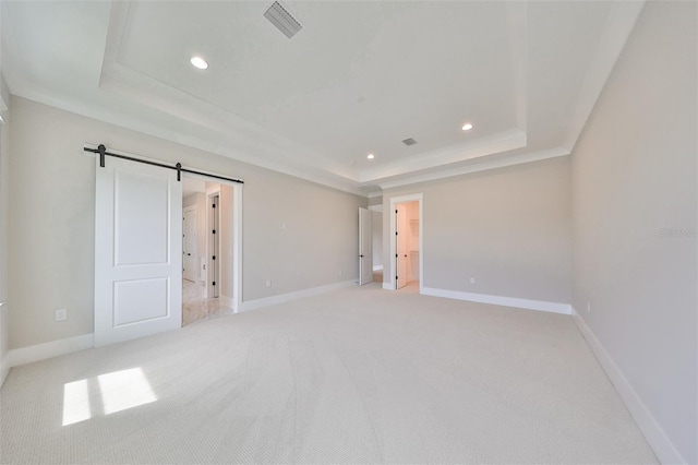 unfurnished bedroom featuring a barn door, a raised ceiling, crown molding, and light carpet