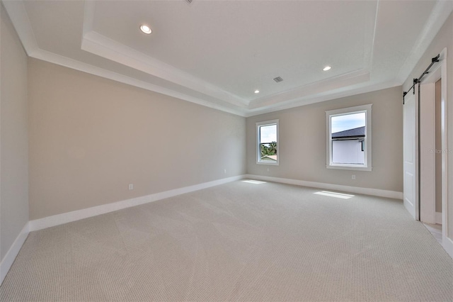 unfurnished room with light colored carpet, a raised ceiling, and a barn door