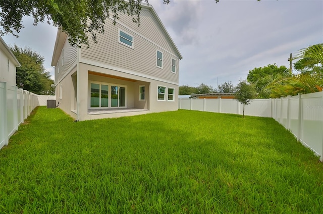 rear view of property with cooling unit, a yard, and a patio area