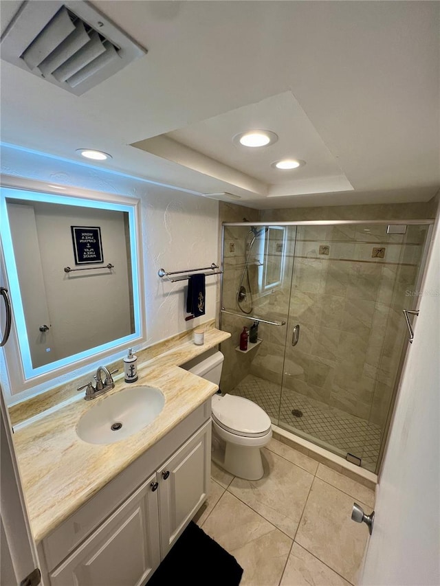 bathroom featuring vanity, toilet, a tray ceiling, and a shower with door