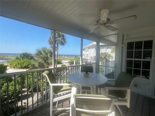 sunroom with ceiling fan and a water view