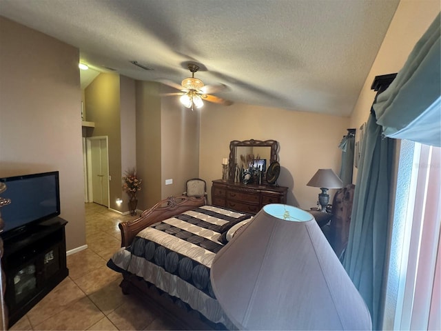 bedroom featuring vaulted ceiling, ceiling fan, light tile patterned floors, and a textured ceiling