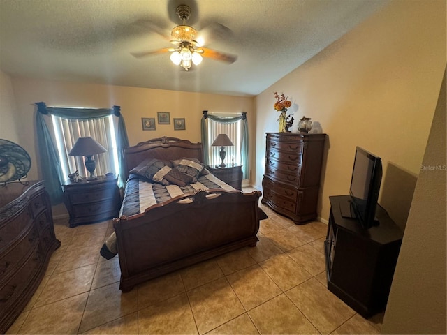 bedroom with ceiling fan, light tile patterned floors, and a textured ceiling